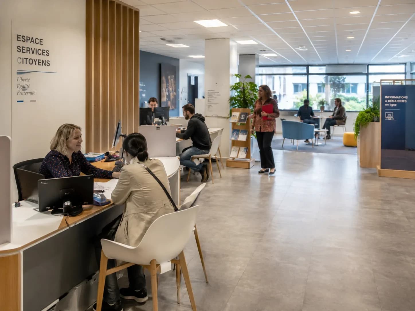 Espace services citoyens en mairie avec agents accueillant des usagers aux bureaux ouverts — HD Media